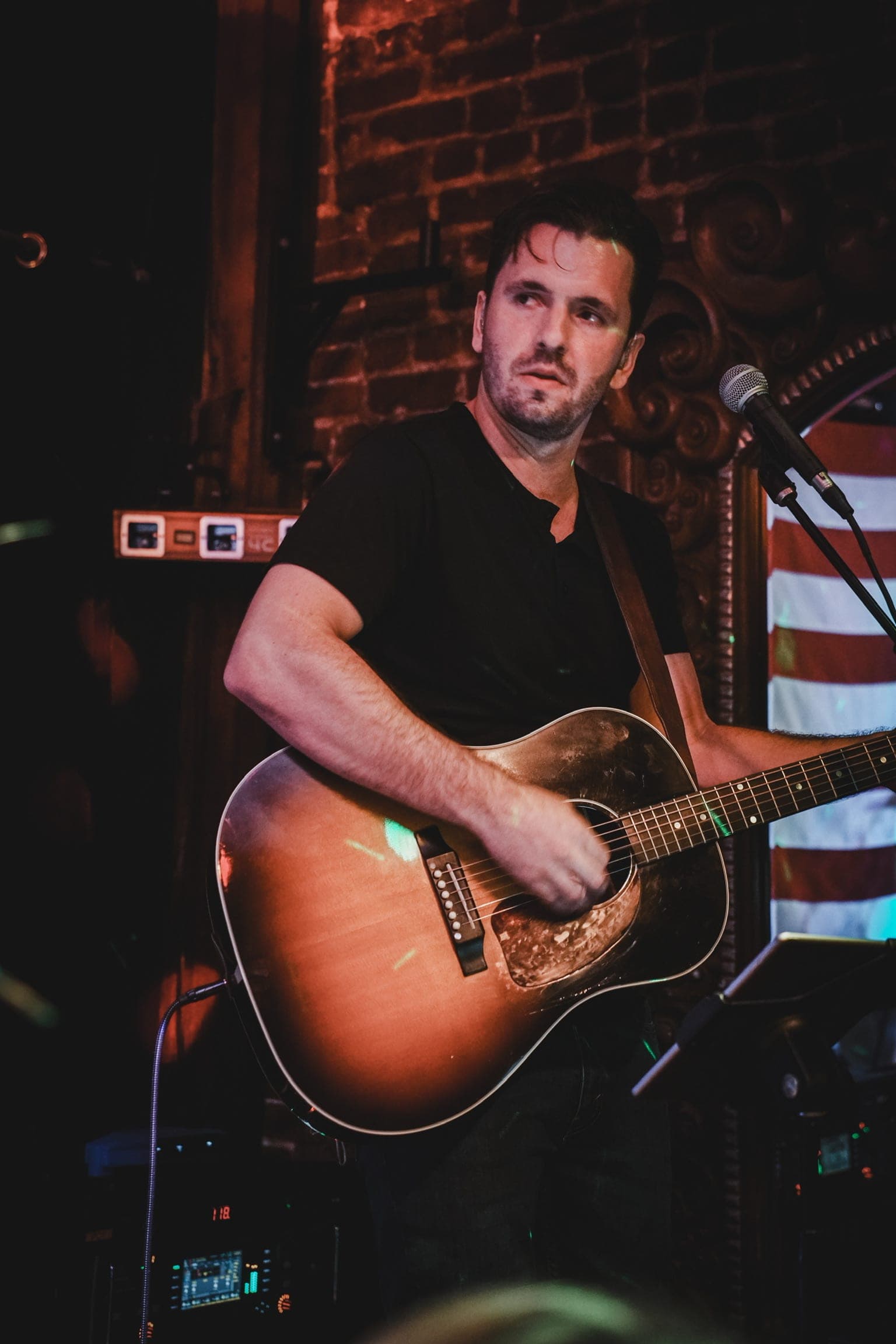 Acoustic guitarist under the red brick and stage light